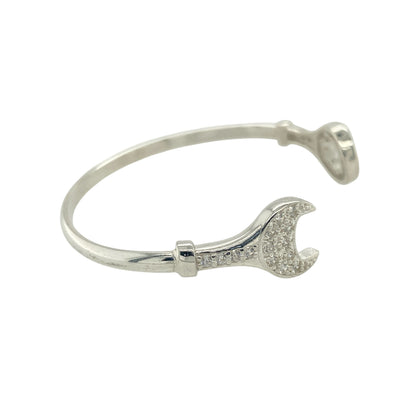 Bring playful personality and sparkling detail to a child’s jewellery collection with this new 925 silver and cubic zirconia set children's spanner bangle—a fun and unique piece with a touch of charm and shine.

Design: The front of the bangle features a detailed 11mm high spanner motif, accented with cubic zirconia stones for a hint of brilliance and whimsy.
Material: Made from solid 925 sterling silver, the polished finish provides a bright, smooth shine that enhances the playful design.
