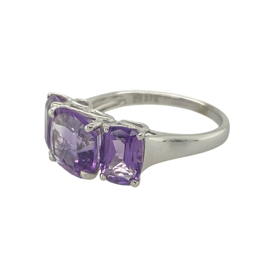 Add bold colour and elegant symmetry to your jewellery collection with this pre-owned 9ct white gold amethyst trilogy ring—vibrant and beautifully balanced.

Design: The ring features an 8mm by 8mm rounded square-cut amethyst at the centre, flanked by two 7mm by 5mm oval-cut amethysts, creating a striking and harmonious trio.
Material: Made from 9-carat white gold, the cool-toned setting enhances the vivid purple hues of the amethysts and offers a modern, polished finish.
