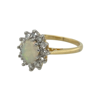 Bring luminous colour and timeless elegance to your collection with this pre-owned 18ct yellow gold diamond and opal cluster ring—an enchanting piece offering refined sparkle and captivating beauty.

Design: This size K–L ring features a 7mm by 5mm oval opal at the centre, displaying its natural play of colour, surrounded by a halo of diamonds that enhance its iridescent glow.
Material: Made from 18-carat yellow gold