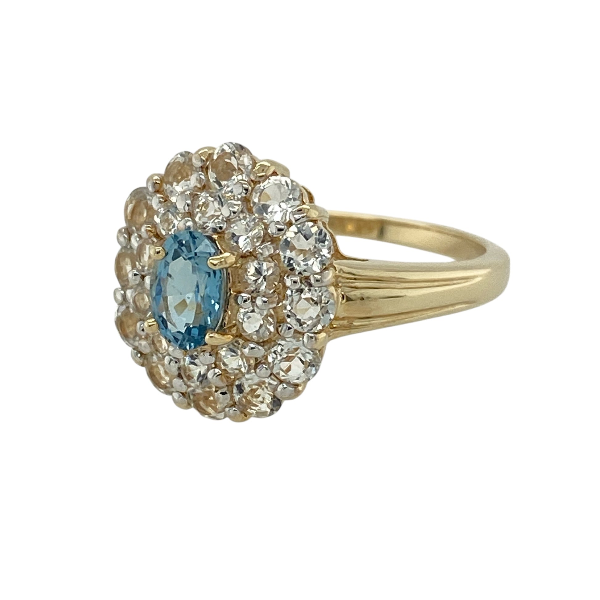 Bring refined colour and elegant sparkle to your jewellery collection with this pre-owned 9ct yellow gold Santa Maria African aquamarine and white topaz cluster ring, a beautifully balanced design with timeless appeal.

Design: This ring features an oval Santa Maria African aquamarine at the centre, surrounded by two rows of white topaz that enhance its soft blue colour and create a striking, layered cluster effect.