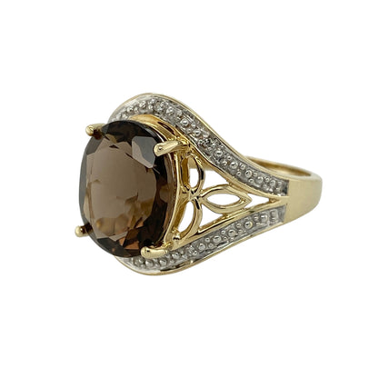 Bring warm tones and elegant sparkle to your jewellery collection with this pre-owned 9ct yellow gold diamond and smoky quartz set halo ring.

Design: The ring features an oval smoky quartz at the centre, measuring approximately 12mm by 10mm, surrounded by a halo of sparkling diamonds that enhance its rich, earthy tones.
Material: Made from 9-carat yellow gold, the warm polished finish beautifully complements the depth of the smoky quartz and the brilliance of the diamonds.