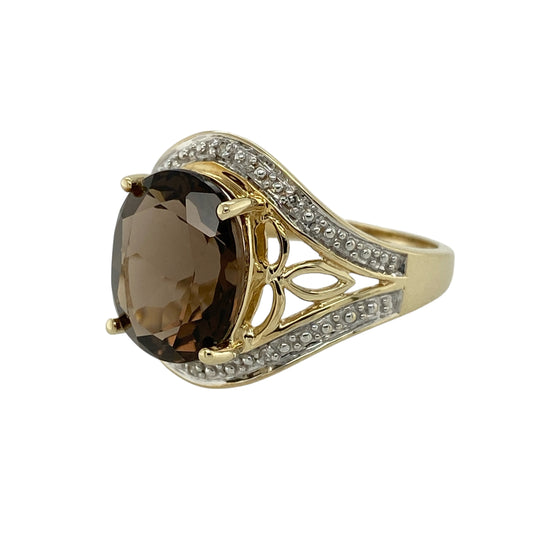 Bring warm tones and elegant sparkle to your jewellery collection with this pre-owned 9ct yellow gold diamond and smoky quartz set halo ring.

Design: The ring features an oval smoky quartz at the centre, measuring approximately 12mm by 10mm, surrounded by a halo of sparkling diamonds that enhance its rich, earthy tones.
Material: Made from 9-carat yellow gold, the warm polished finish beautifully complements the depth of the smoky quartz and the brilliance of the diamonds.