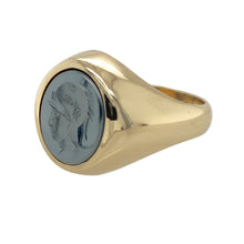 Load image into Gallery viewer, Add a bold and distinguished piece to your jewellery collection with this pre-owned 9ct yellow gold &amp; hematite centurion oval signet ring, featuring:

Design: A striking oval signet ring showcasing a detailed centurion intaglio carved into hematite for a classic, powerful look.
Material: 9-carat yellow gold, offering a warm and polished finish that complements the dark sheen of the stone.
Gemstone Detail: Set with an impressive 11mm by 10mm hematite stone, adding depth and character.

