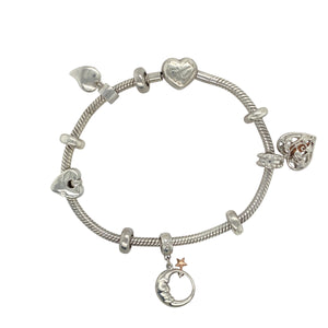 Add a meaningful and elegant touch to your jewellery collection with this pre-owned 925 silver Clogau charm bracelet with 9ct rose gold accents.

Design: This stunning charm bracelet features a heart-shaped Tree of Life charm, a moon with star charm, another Tree of Life heart charm, and a heart charm, symbolising love, nature, and the celestial. Five stoppers are included to keep the charms spaced out and secure.
Material: Made from 925 silver with 9ct rose gold accents