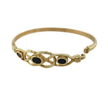 Load image into Gallery viewer, Add a touch of heritage and elegance to your jewellery collection with this pre-owned 9ct yellow gold &amp; black stone set Celtic bangle.

Design: A beautifully crafted Celtic-inspired bangle featuring an intricate design with a striking black stone at the center.
Material: Made from 9-carat yellow gold, offering a rich, warm finish that complements the bold contrast of the black stone.
Gemstone Detail: The centerpiece is a 6mm by 4mm black stone, set within the detailed Celtic design for a timeless look.

