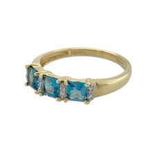 Load image into Gallery viewer, Bring a fresh pop of colour to your collection with this pre-owned 9ct yellow gold diamond and blue topaz band ring, featuring:

Design: A sleek band style set with alternating gemstones, combining vibrant colour with subtle sparkle.
Material: 9-carat yellow gold, offering a classic warm tone and polished finish.
Gemstone Detail: Set with square-cut blue topaz stones, each measuring approximately 4mm by 4mm, enhanced by sparkling diamonds for added brilliance.

