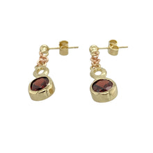 Load image into Gallery viewer, Add rich colour and Celtic charm to your collection with these pre-owned 9ct yellow and rose gold garnet set drop earrings, featuring:

Design: A beautifully detailed Celtic-inspired design, blending yellow and rose gold tones with intricate openwork and flowing curves.
Material: 9-carat yellow and rose gold, offering a warm, polished finish with a subtle two-tone contrast.
Gemstone Detail: Each earring is set with a deep red garnet measuring 7mm by 5mm, adding a striking pop of colour and vintage appeal.

