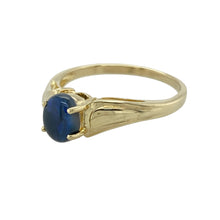 Load image into Gallery viewer, Introduce a touch of rich colour and smooth elegance to your collection with this pre-owned 9ct yellow gold ring, set with a polished oval blue cabochon, offering timeless style with a refined finish, featuring:

Design: A simple yet striking design, featuring a smooth oval cabochon stone in a polished setting that highlights its rich, glossy surface.
Material: Made from 9-carat yellow gold, the warm tone beautifully complements the cool depth of the blue stone.

