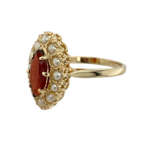 Add a touch of antique-style elegance to your collection with this pre-owned 9ct yellow gold garnet and seed pearl set cluster ring, combining deep colour with delicate detail, featuring:

Design: A refined cluster style ring centred around a marquise-cut garnet, framed by a halo of seed pearls for a timeless, vintage-inspired look.
Material: Made from 9-carat yellow gold, the polished finish enhances the rich tones of the garnet and the soft lustre of the pearls.

