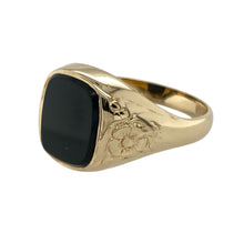 Load image into Gallery viewer, Make a statement with this pre-owned 9ct yellow gold and onyx set signet ring, combining classic form with intricate detail and deep, rich contrast, featuring:

Design: A traditional signet ring with a rectangular onyx stone at the centre, flanked by beautifully patterned shoulders featuring a subtle floral motif for added elegance.
Material: Made from 9-carat yellow gold, the polished finish enhances the depth of the onyx and the detail in the shoulder design.
