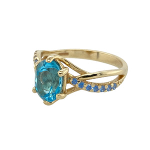 Add a splash of colour and refined sparkle to your collection with this pre-owned 9ct yellow gold blue topaz and tanzanite set ring, combining cool hues with elegant design, featuring:

Design: A graceful setting with a vibrant oval blue topaz at the centre, complemented by twisted shoulders adorned with small tanzanite stones for added colour and sparkle.
Material: Made from 9-carat yellow gold, the polished finish enhances the contrast between the golden tones and the cool blues of the gemstones.

