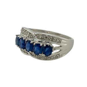 Add elegance and movement to your collection with this pre-owned 9ct white gold diamond and sapphire set crossover band ring, offering a flowing design with rich colour and sparkle, featuring:

Design: A stylish crossover band ring with a sweeping design that features diamonds along the top and bottom curves, and three oval-cut sapphires nestled at the centre for a striking layered effect.
Material: Made from 9-carat white gold, the polished finish gives a cool