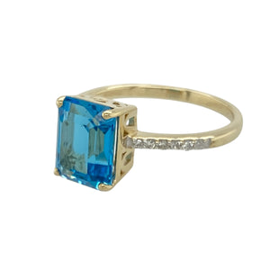 Bring vibrant elegance and refined sparkle to your collection with this pre-owned 9ct yellow gold diamond and blue topaz set ring, featuring a bold centre stone and timeless design—perfect for standout occasions or everyday sophistication.

Design: The ring showcases a striking 9mm by 7mm rectangular blue topaz at the centre, framed by diamond-set shoulders that add brilliance and balance to the vivid blue hue.
Material: Made from 9-carat yellow gold