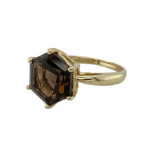 Load image into Gallery viewer, Bring earthy elegance and bold character to your collection with this pre-owned 9ct yellow gold smoky quartz set ring, featuring a striking hexagon-shaped gemstone—perfect for vintage-inspired styling or unique everyday wear.

Design: The ring features a 12mm hexagon-cut smoky quartz stone, offering rich, warm tones and geometric charm in a bold, eye-catching setting.
Material: Made from 9-carat yellow gold, the polished finish enhances the depth of the smoky quartz and adds warmth to the overall design.

