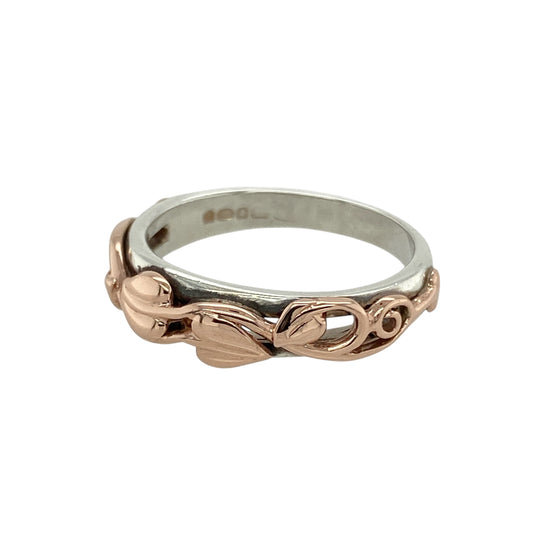 Bring symbolic beauty and timeless craftsmanship to your collection with this pre-owned 925 silver and 9ct rose gold Clogau Tree of Life band ring, featuring elegant detail and meaningful design—perfect for everyday wear or a thoughtful gift.

Design: The ring showcases Clogau’s signature Tree of Life motif across the front of the 5mm wide band, symbolising growth, strength, and continuity through flowing vine and leaf patterns.
