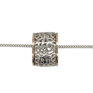 Bring floral elegance and distinctive charm to your collection with this pre-owned 925 silver with 9ct rose gold Clogau rose patterned barrel pendant on an 18" Clogau curb chain, featuring detailed craftsmanship in a bold design—perfect for everyday wear or special gifting.

Design: The pendant features a barrel shape measuring 11mm long and 15mm in diameter, adorned with intricate rose patterns and accented with Clogau’s signature 9ct Welsh rose gold detailing.
