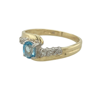 Add a touch of vibrant elegance to your jewellery collection with this pre-owned 9ct yellow gold diamond and blue topaz twist ring—designed to bring colour, sparkle, and style to any occasion.

Design: Featuring a 5mm by 4mm oval-cut blue topaz at the centre, the ring is accented with a subtle diamond and a graceful twist design, where the bands sweep above and below the gemstone for a flowing, modern silhouette.
