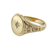 Load image into Gallery viewer, Make a bold and distinguished statement with this pre-owned 9ct yellow gold diamond set oval signet ring—refined design with classic heritage appeal.

Design: The ring features a 15mm high oval face with a single diamond accent, framed by detailed patterned shoulders that add texture and sophistication.
Material: Made from 9-carat yellow gold, the polished finish enhances the engraving and complements the subtle sparkle of the diamond.


