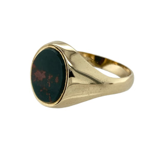 Add classic distinction and deep colour to your collection with this pre-owned 9ct yellow gold and bloodstone oval signet ring—refined, traditional, and full of character.

Design: This timeless signet ring features a 12mm by 10mm oval bloodstone, known for its rich green hue with natural red flecks, set in a polished gold bezel for a bold, elegant look.
Material: Made from 9-carat yellow gold, the smooth finish enhances the depth of the bloodstone and offers a warm, luxurious glow.
