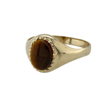 Load image into Gallery viewer, Add warmth and natural elegance to your collection with this pre-owned 9ct yellow gold and tiger’s eye oval signet ring—subtle, stylish, and full of earthy charm.

Design: This classic signet ring features an 8mm by 6mm oval tiger’s eye stone, showcasing its signature golden-brown chatoyancy, set within a smooth yellow gold bezel for a refined finish.
Material: Made from 9-carat yellow gold, the polished setting complements the rich tones of the tiger’s eye and adds a soft, radiant glow.

