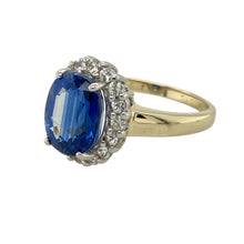 Load image into Gallery viewer, Add vintage-inspired glamour and rich colour to your collection with this pre-owned 9ct yellow gold blue stone and cubic zirconia set cluster ring—bold, elegant, and perfect for statement styling.

Design: The ring features a striking 10mm by 8mm sapphire-coloured central stone, surrounded by a sparkling halo of cubic zirconia in a classic cluster setting.
Material: Made from 9-carat yellow gold, the polished finish enhances the deep blue hue of the centre stone
