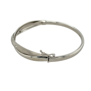Add modern elegance and subtle sparkle to your collection with this pre-owned 9ct white gold cubic zirconia set crossover bangle—contemporary in design and perfect for everyday sophistication.

Design: The bangle features a stylish crossover front where two 4mm bands intersect—one polished and set with cubic zirconia for sparkle, the other with a brushed finish for contrast and texture.
