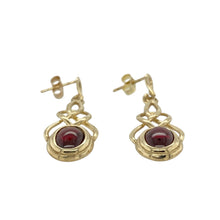 Load image into Gallery viewer, Add rich colour and symbolic detail to your collection with these pre-owned 9ct yellow gold dark red stone Celtic knot drop earrings—elegant, meaningful, and full of timeless charm.

Design: Each earring features a 7mm by 5mm oval dark red stone, suspended beneath an intricate Celtic knot design that symbolises eternity and unity.
Material: Made from 9-carat yellow gold, the polished finish enhances the deep red hue of the stones and the fine detail of the knotwork.

