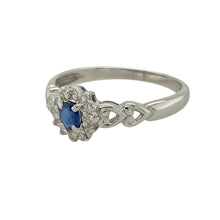 Load image into Gallery viewer, Bring romantic detail and classic sparkle to your collection with this pre-owned 9ct white gold cluster ring, featuring a vibrant sapphire centre and delicate heart-shaped shoulders—perfect for timeless elegance with a sentimental touch.

Design: The ring features a 4mm by 3mm oval-cut sapphire at the centre, surrounded by a sparkling diamond halo. The shoulders of the band are styled with an open heart pattern, adding charm and graceful detail to the setting.

