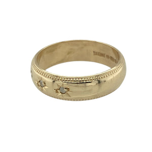 Add subtle sparkle and vintage-inspired detail to your collection with this pre-owned 9ct yellow gold diamond set band ring—perfect for everyday elegance with classic charm.

Design: The 5mm wide band features three small diamonds set in starburst settings across the front, framed by delicate milgrain edging for a refined, traditional look.
Material: Made from 9-carat yellow gold, the polished finish enhances the warm tone of the band and highlights the fine detailing.
