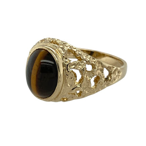 Add natural richness and vintage style to your collection with this pre-owned 9ct yellow gold and tiger’s eye oval signet ring—perfect for bold character with timeless charm.

Design: The ring features a 10mm by 8mm oval tiger’s eye stone, showcasing its golden-brown bands and signature chatoyancy, framed by open patterned shoulders for added visual interest.
Material: Made from 9-carat yellow gold, the polished finish enhances the warm tones of the metal and complements the earthy shimmer of the stone.
