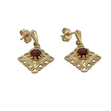 Load image into Gallery viewer, Bring rich colour and ornate detail to your collection with these pre-owned 9ct yellow gold and garnet fancy drop earrings—elegant and timeless with a touch of vintage flair.

Design: Each earring features a 6mm by 4mm oval-cut garnet, set within an intricate drop design that adds graceful movement and charm.
Material: Made from 9-carat yellow gold, the warm setting enhances the deep red tones of the garnets for a striking contrast.

