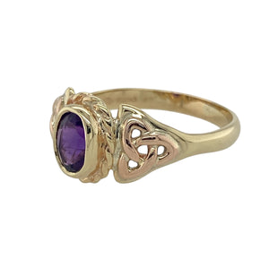 Bring heritage style and rich colour to your collection with this pre-owned 9ct yellow and rose Welsh gold Celtic ring set with amethyst—a meaningful design with timeless elegance.

Design: This striking ring features a 7mm by 5mm oval-cut amethyst at its centre, framed by traditional Celtic knotwork that adds depth and symbolism.
Material: Made from a blend of 9-carat yellow and rare rose Welsh gold, the dual tones enhance the regal purple of the amethyst with warm contrast.
