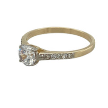 Load image into Gallery viewer, Bring classic sparkle and graceful style to your collection with this pre-owned 9ct yellow gold and cubic zirconia solitaire ring—elegant and eye-catching with timeless appeal.

Design: This ring features a 6mm round cubic zirconia at the centre, complemented by smaller stones set along the shoulders for added brilliance.
Material: Made from 9-carat yellow gold, the polished finish enhances the sparkle of the stones with warm, refined contrast.

