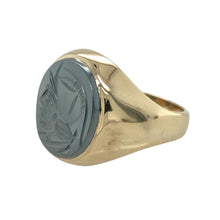 Load image into Gallery viewer, Bring bold character and timeless strength to your collection with this pre-owned 9ct yellow gold and hematite centurion set oval signet ring, offering a striking design and powerful presence—perfect for making a distinguished statement.

Design: The ring features an impressive oval hematite stone measuring 14mm by 12mm, engraved with a centurion motif that adds depth and historical charm. The dark metallic sheen of the hematite contrasts beautifully with the warm glow of the gold.

