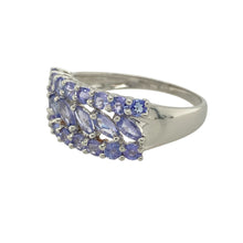 Load image into Gallery viewer, Bring vibrant colour and bold elegance to your collection with this pre-owned 9ct white gold and tanzanite set three row wide band ring, offering a striking design and sophisticated presence—perfect for making a standout statement.

Design: The ring features a wide front measuring 10mm high, beautifully set with a combination of round-cut and marquise-cut tanzanite stones arranged in three rows. The rich violet-blue tones create a captivating, luxurious focal point.

