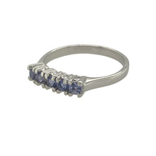 Load image into Gallery viewer, Bring vibrant colour and modern elegance to your collection with this pre-owned 9ct white gold and tanzanite set band ring, offering a refined blend of delicate sparkle and contemporary charm—perfect for adding a touch of sophistication to any look.

Design: The ring features a series of tanzanite stones, each measuring 2mm in diameter, set across the band to create a continuous line of soft violet-blue brilliance.

