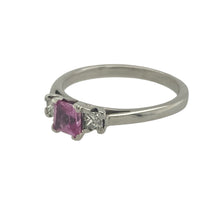 Load image into Gallery viewer, Bring delicate colour and timeless sparkle to your collection with this pre-owned 18ct white gold diamond and pink sapphire set trilogy ring, offering elegant contrast and refined brilliance — perfect for meaningful moments or everyday luxury.

Design: The ring features a central 4mm x 4mm princess-cut pink sapphire, flanked by two small diamonds of approximately 0.06ct each, creating a graceful and balanced trilogy design.

