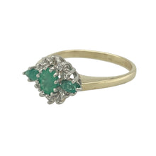 Load image into Gallery viewer, Bring vintage elegance and rich colour to your collection with this pre-owned 9ct yellow gold diamond and emerald set cluster ring, offering timeless sparkle and refined detail — perfect for special occasions or meaningful everyday wear.

Design: The ring features a central 5mm x 4mm oval emerald, surrounded by a sparkling cluster of diamonds, with an additional emerald stone set into each shoulder for a beautifully balanced and classic look.

