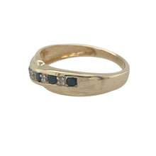 Load image into Gallery viewer, Add a touch of graceful movement and classic contrast with this pre-owned 9ct yellow gold crossover band ring, set with sapphires and diamonds for elegant sparkle.

Design: The 5mm wide front features a flowing crossover design with alternating sapphires and diamonds, creating a timeless blend of deep blue and bright brilliance.
Material: Made from 9-carat yellow gold, the polished band enhances the colours of the stones while offering a soft, radiant finish.

