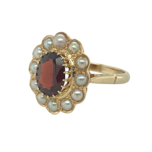 Add antique-inspired elegance to your collection with this pre-owned 9ct yellow gold garnet and pearl cluster ring—rich in colour and timeless charm.

Design: The ring features a 9mm by 7mm oval garnet at the centre, surrounded by a halo of creamy pearls in a classic vintage-style cluster setting.
Material: Made from 9-carat yellow gold, the warm tone complements the deep red of the garnet and the soft lustre of the surrounding pearls.
