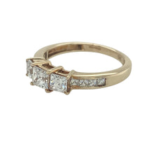 Load image into Gallery viewer, Add classic sparkle and symbolic style to your collection with this pre-owned 9ct yellow gold cubic zirconia trilogy ring—elegant, timeless, and full of brilliance.

Design: The ring features a central trio of cubic zirconia stones symbolising past, present, and future, with additional smaller stones set along the shoulders for extra sparkle.
Material: Made from 9-carat yellow gold, the polished finish provides a warm glow that enhances the clarity and brilliance of the stones.

