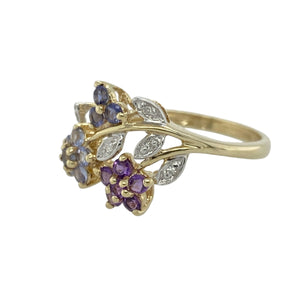 Bring colour and delicate charm to your collection with this pre-owned 9ct yellow gold diamond and gemstone flower vine ring—whimsical, elegant, and full of natural beauty.

Design: The front of the ring measures 12mm high and features a graceful vine design set with tanzanite, amethyst, and sapphire stones, accented by small diamonds for subtle sparkle.
Material: Made from 9-carat yellow gold, the polished finish enhances the vibrant hues of the gemstones and the fluid lines of the floral motif.

