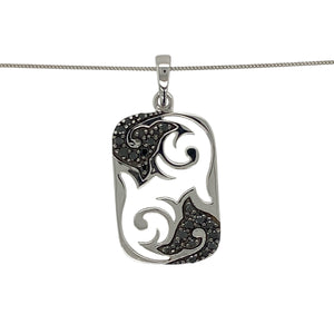 Add modern edge and refined detail to your look with this pre-owned 9ct white gold black diamond tag pendant necklace—stylish, distinctive, and full of character.

Design: The 2.9cm long pendant features an open cut-out pattern on a sleek tag shape, accented with a black diamond for a subtle touch of contrast and sparkle.
Material: Made from 9-carat white gold, the polished finish highlights the contemporary design and complements the depth of the black diamond.

