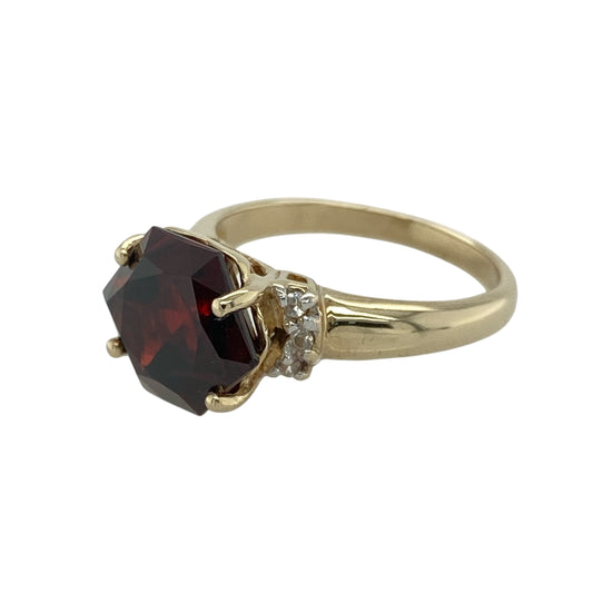 Rich in colour and vintage charm, this pre-owned 9ct yellow gold garnet and cubic zirconia ring offers a bold centrepiece with elegant sparkle—ideal for statement wear or meaningful gifting.

Design: The ring features a striking six-sided garnet measuring 10mm in height, flanked by two small cubic zirconia stones that add subtle brilliance to the bold centre.
Material: Made from 9-carat yellow gold, the polished finish complements the deep red of the garnet and enhances the sparkle of the accent stones.
