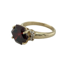 Load image into Gallery viewer, Rich in colour and vintage charm, this pre-owned 9ct yellow gold garnet and cubic zirconia ring offers a bold centrepiece with elegant sparkle—ideal for statement wear or meaningful gifting.

Design: The ring features a striking six-sided garnet measuring 10mm in height, flanked by two small cubic zirconia stones that add subtle brilliance to the bold centre.
Material: Made from 9-carat yellow gold, the polished finish complements the deep red of the garnet and enhances the sparkle of the accent stones.

