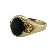 Load image into Gallery viewer, Bold and refined, this pre-owned 9ct yellow gold onyx signet ring combines striking contrast with classic detailing—perfect for everyday style or symbolic significance.

Design: The ring features a 10mm by 8mm oval onyx stone set at the centre, framed by fleur-de-lis detailing on each shoulder for a touch of heritage style.
Material: Made from 9-carat yellow gold, the polished finish contrasts beautifully with the deep black of the onyx.

