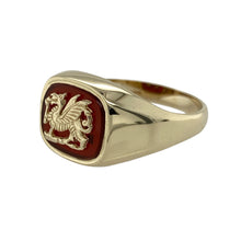 Load image into Gallery viewer, Bold and symbolic, this pre-owned 9ct yellow gold signet ring features a striking red stone and detailed Welsh dragon design—perfect for those who appreciate heritage, strength, and standout style.

Design: The ring showcases a 10mm by 12mm carnelian-coloured red stone backing a finely detailed Welsh dragon emblem, creating a powerful and eye-catching centrepiece.
Material: Made from 9-carat yellow gold, the polished finish highlights the warmth of the gold and contrasts beautifully with the deep red stone.
