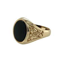 Load image into Gallery viewer, Delicate yet bold, this pre-owned 9ct yellow gold onyx signet ring features a floral-inspired design with rich contrast—perfect for those who love timeless pieces with a touch of detail.

Design: The ring showcases a 10mm by 8mm oval onyx stone set into a polished gold frame, with floral-style engraving on the shoulders adding a soft, decorative touch.
Material: Made from 9-carat yellow gold, the polished finish highlights the dark elegance of the onyx and the fine floral detailing.

