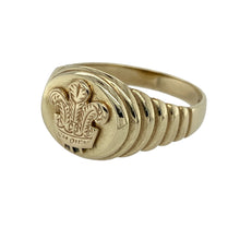Load image into Gallery viewer, Bring heritage style and bold presence to your collection with this pre-owned 9ct yellow gold three feathers oval signet ring—perfect for those who appreciate meaningful symbolism and timeless design.

Design: The ring features a 13mm high oval face engraved with the iconic three feathers emblem, adding historic and cultural significance.
Material: Made from 9-carat yellow gold, the polished finish enhances the warm tone and highlights the detailed engraving.

