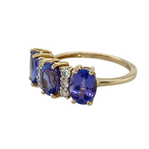 Bring vibrant colour and elegant sparkle to your collection with this pre-owned 14ct yellow gold diamond and tanzanite ring—perfect for special occasions or adding a touch of luxury to everyday wear.

Design: The ring features three oval tanzanite stones, each measuring 8mm by 6mm, with diamonds set in between for added brilliance and contrast.
Material: Made from 14-carat yellow gold, the polished finish enhances the rich purple-blue tones of the tanzanite and the sparkle of the diamonds.
